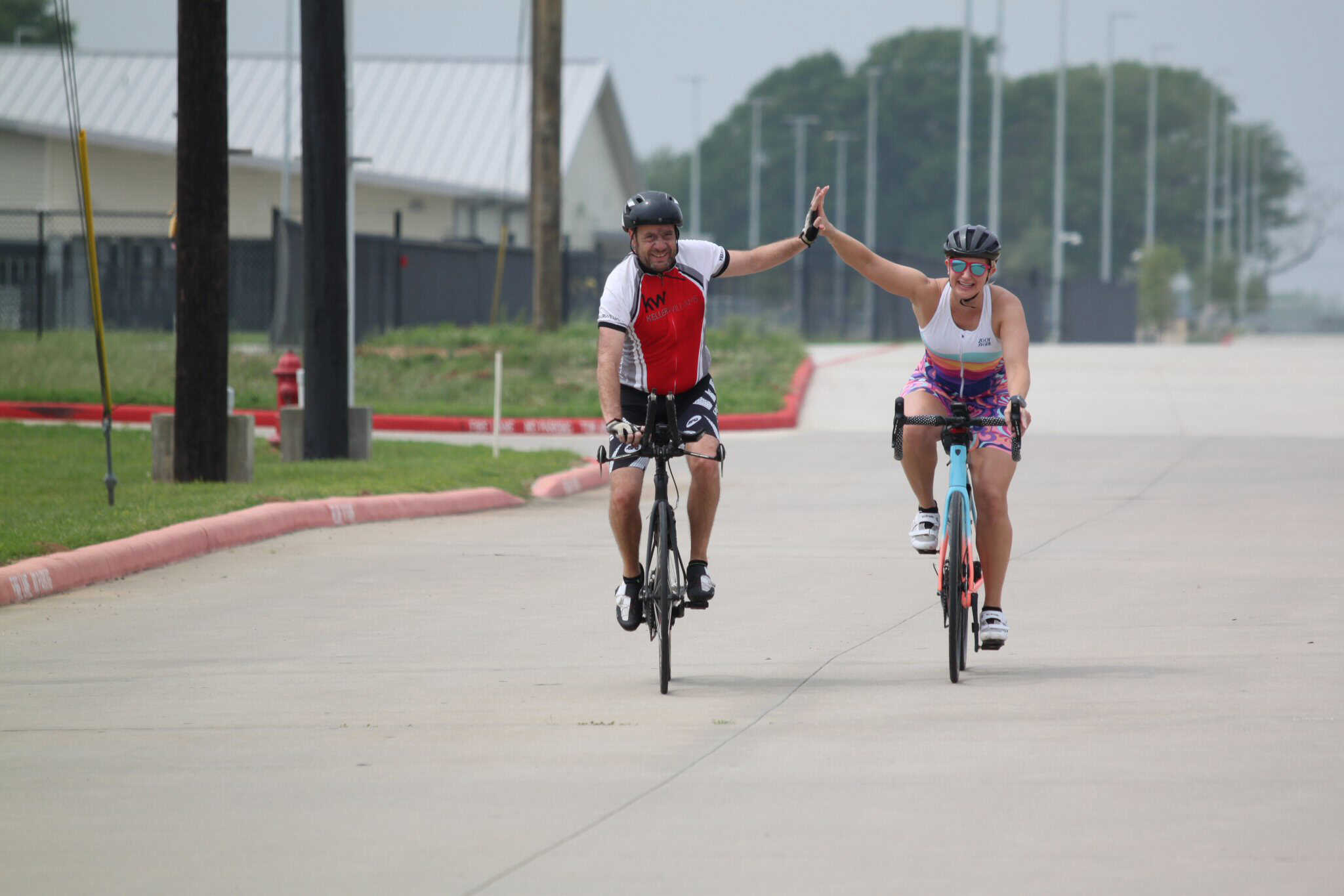 High-energy cyclists sharing a victory high-five on the road during a Bluebonnet Express bike ride.