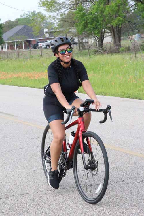 Bright woman in cycling gear riding a bicycle on a suburban street.