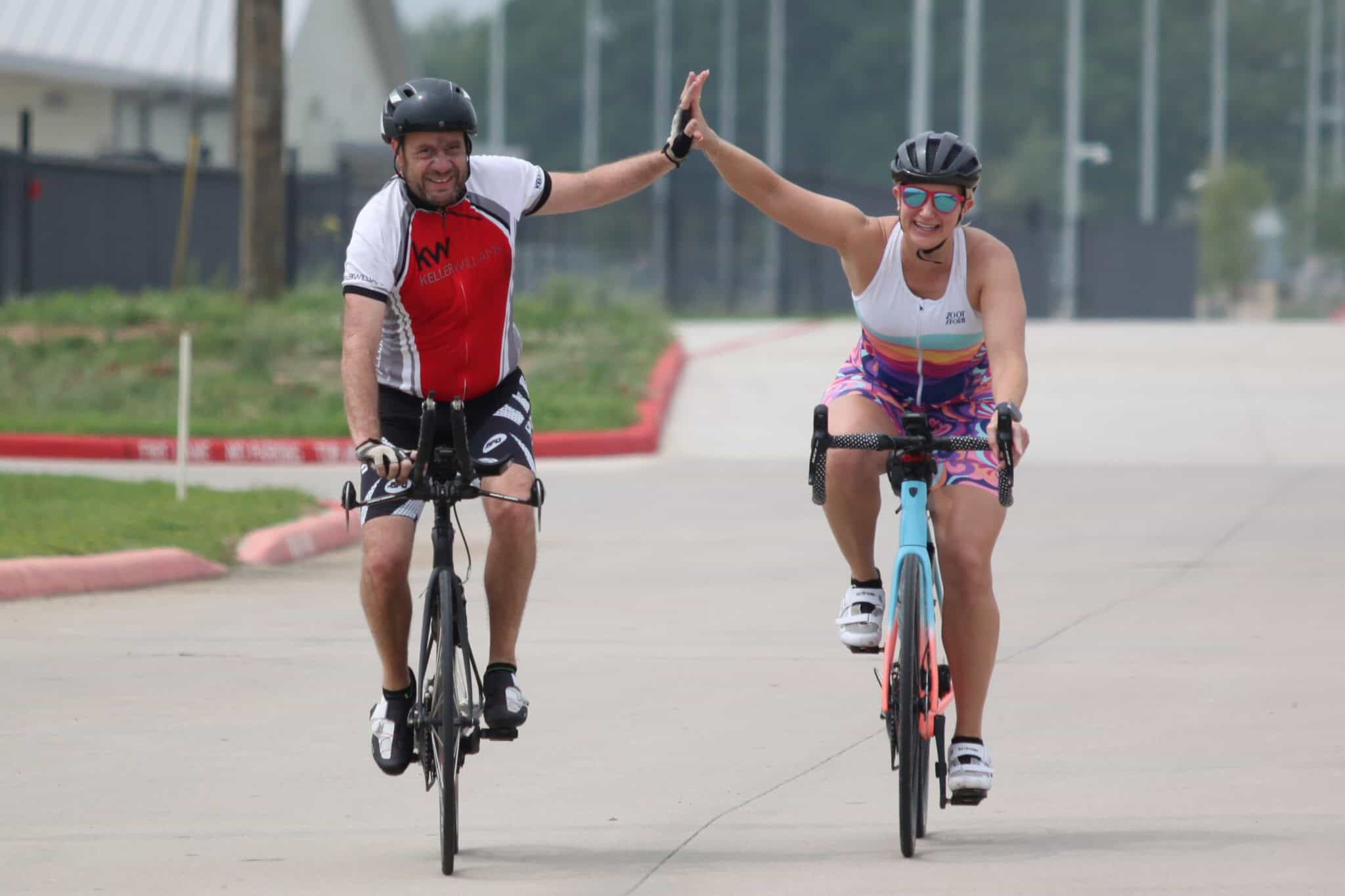 High-energy cyclists sharing a celebratory high-five during a ride on the Bluebonnet Express route.