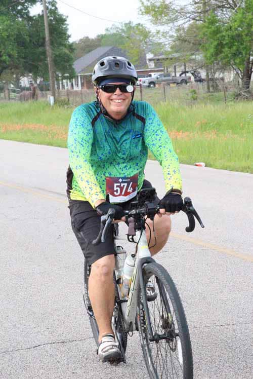 Bright woman cycling in Bluebonnet Express event, wearing helmet and sports gear.