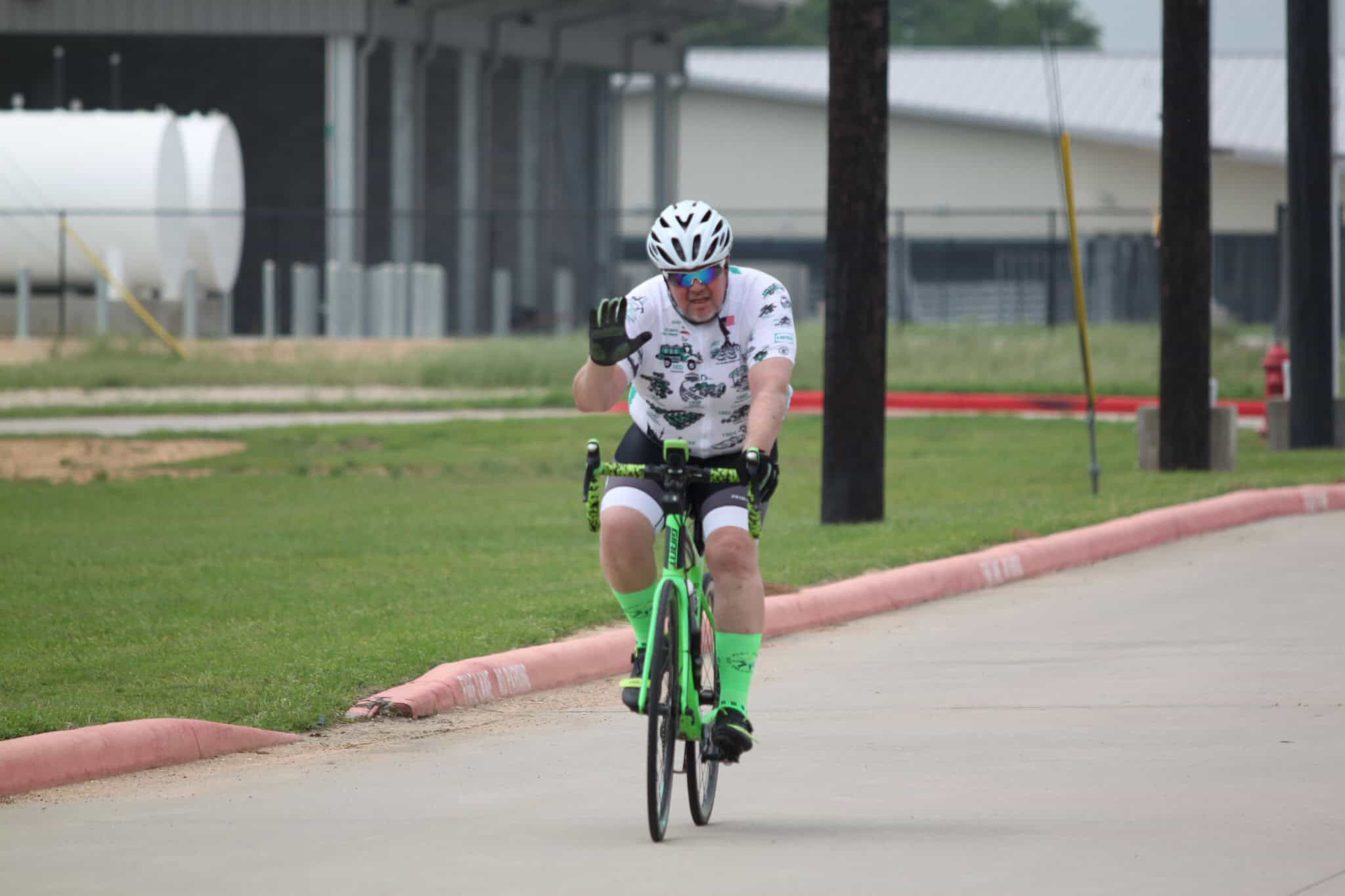 Bright green road bicycle with cyclist riding on paved path, promoting Bluebonnet Express bike service.