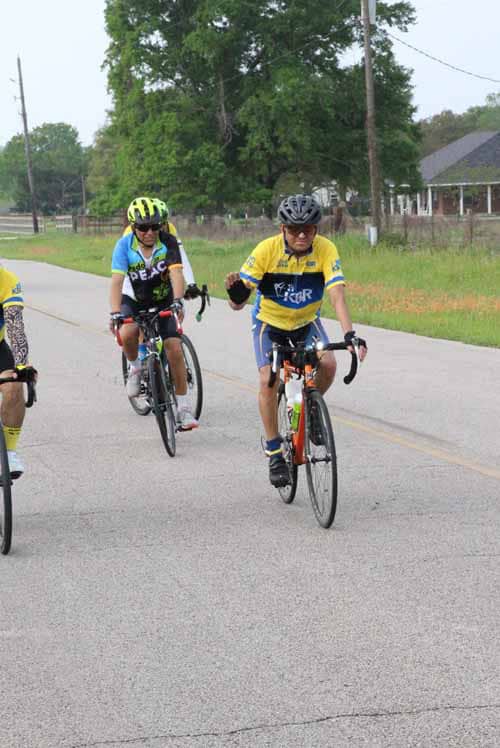 Kids cycling event on rural road with participants wearing colorful jerseys and helmets.