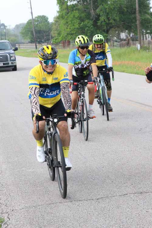 Bright yellow and blue cyclist jerseys at Bluebonnet Express cycling event, few riders on the country road.