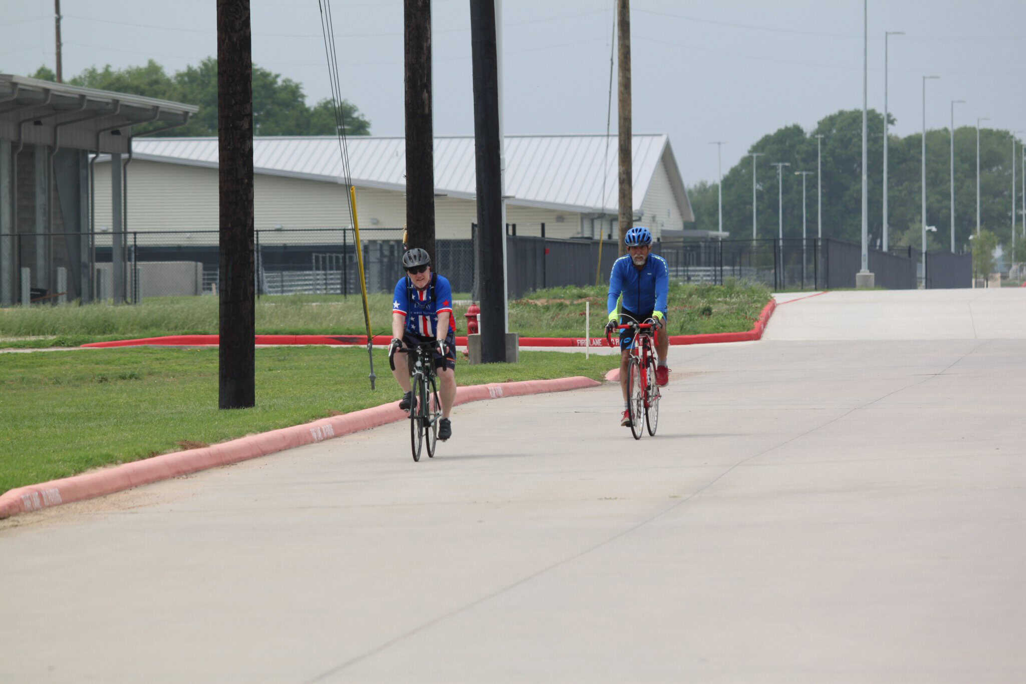 Riders cycling on a paved path with safety gear, enjoying outdoor bike riding at Bluebonnet Express.