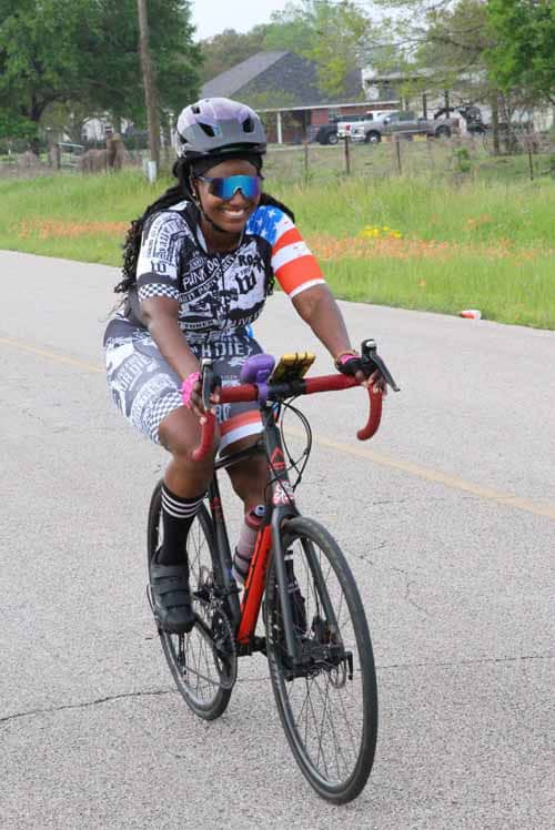 Vibrant cyclist wearing patriotic gear riding on road for Bluebonnet Express event.