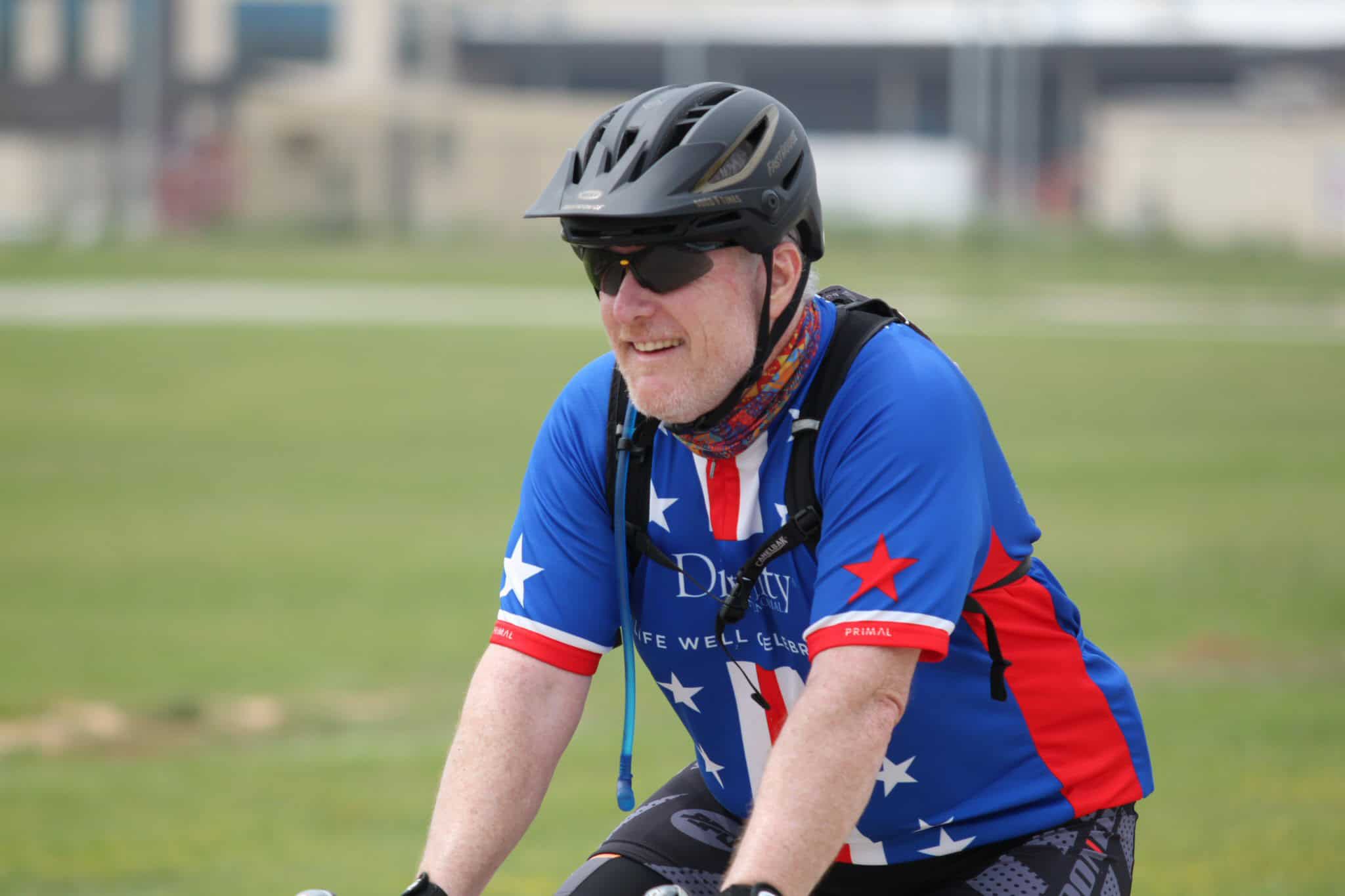 Helmeted cyclist riding on grass fields with Bluebonnet Express branding.