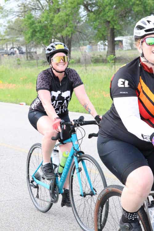 Bright female cyclist riding a blue bicycle during Bluebonnet Express event in spring.
