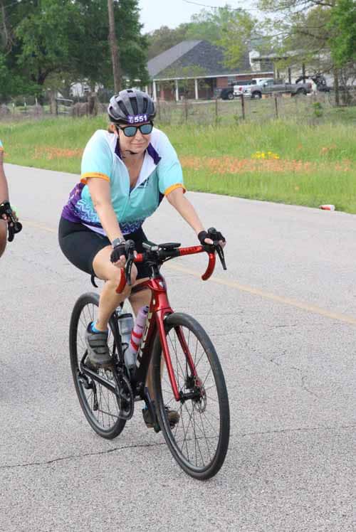 Bright blue cyclist jersey and helmet on red road bike during outdoor ride.