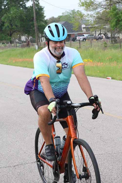 Man riding road bike with blue helmet on suburban street during daytime.