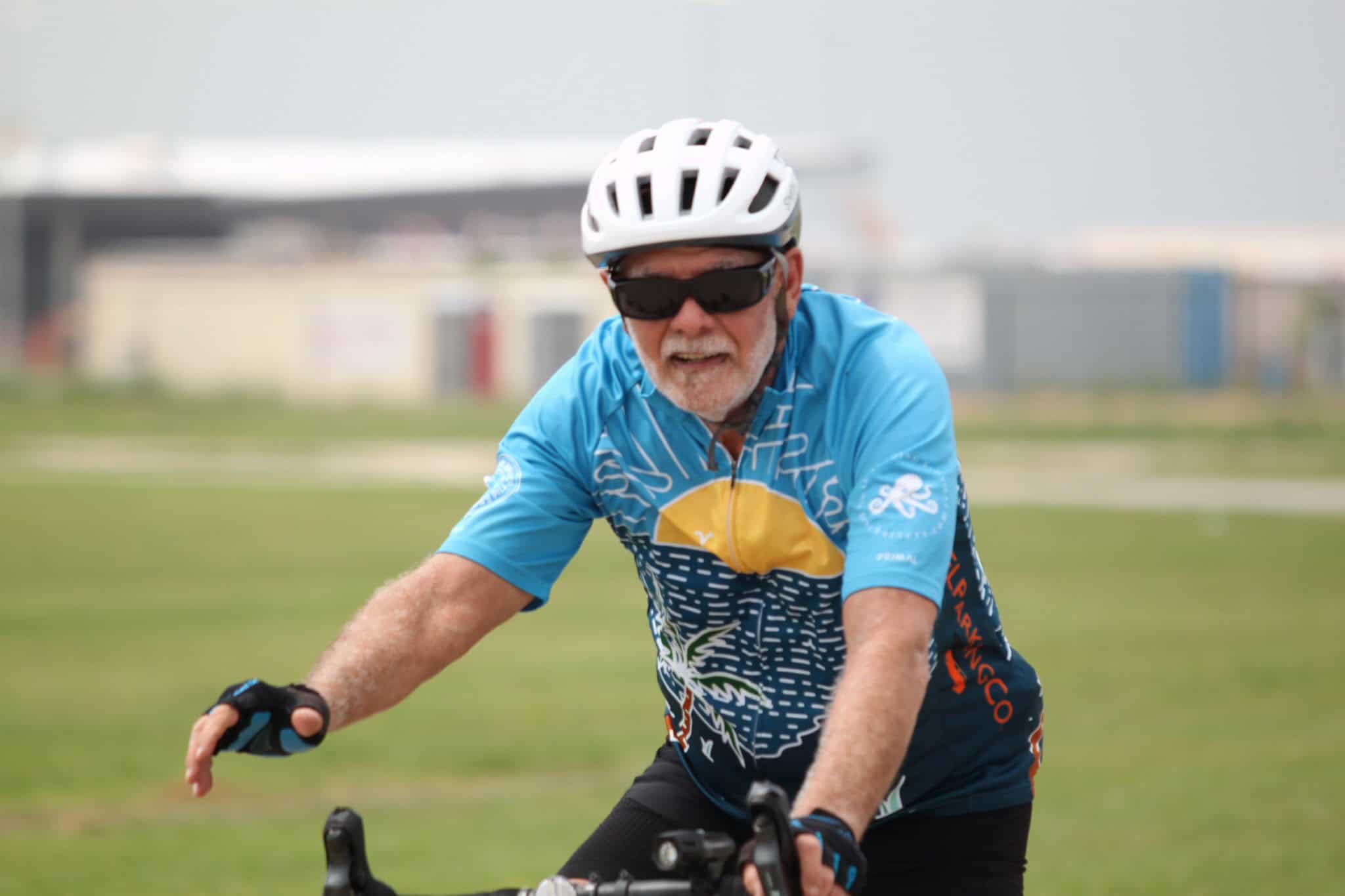 Age-friendly cyclist riding a bike wearing a blue jersey and helmet for Bluebonnet Express event.