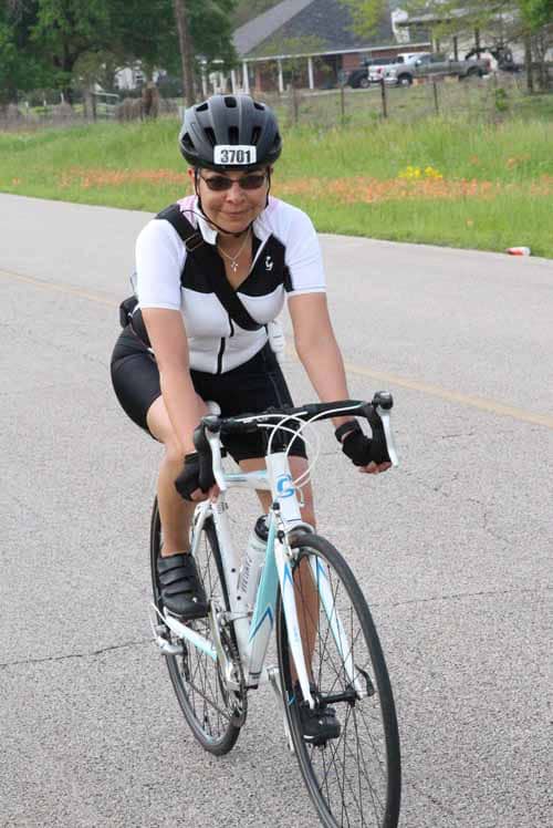 Young woman cyclist riding on road during outdoor bike event.