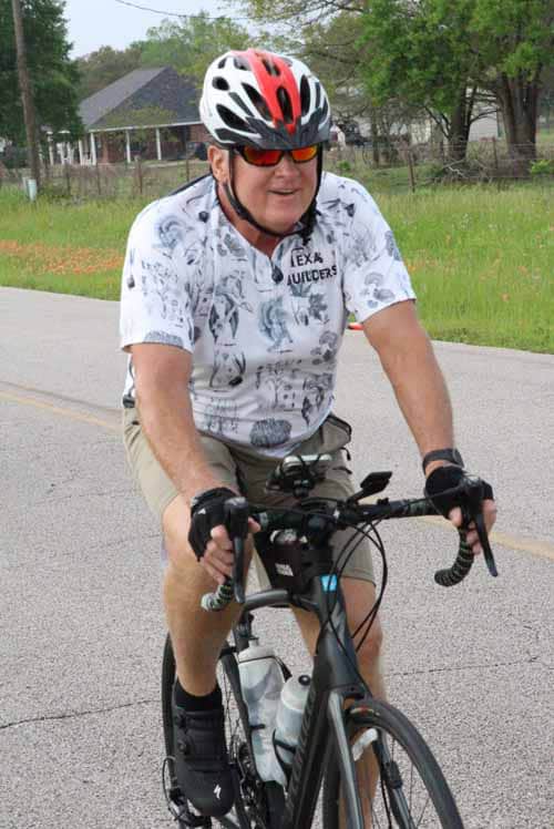 Bicycle rider wearing helmet and sunglasses riding on a suburban road near Bluebonnet Express.
