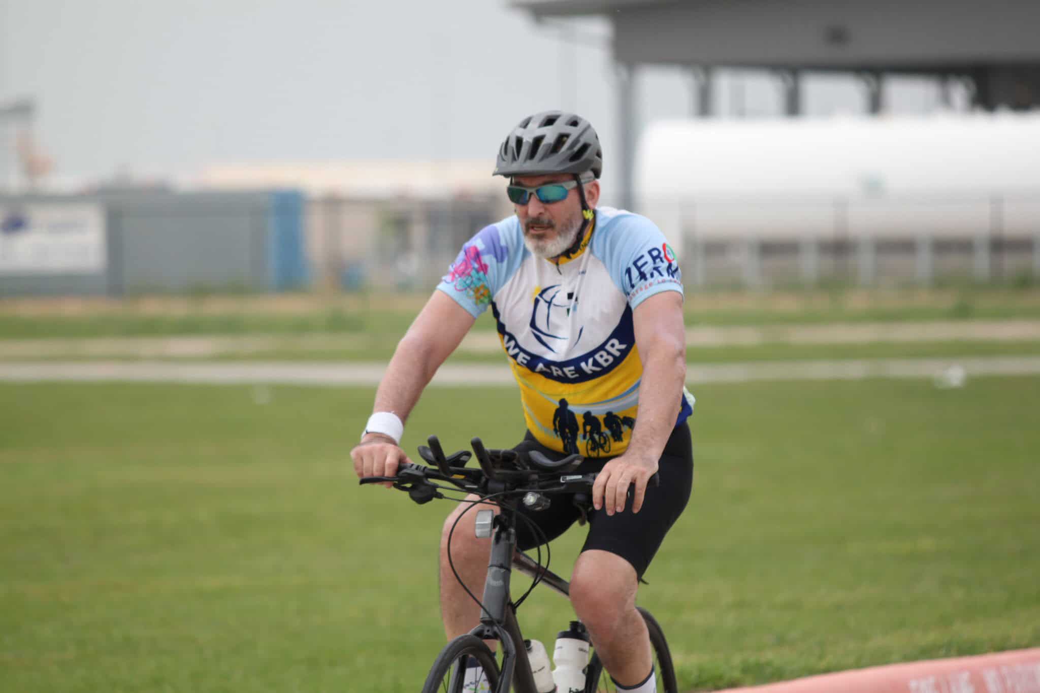 Vibrant cyclist riding on grassy field with Bluebonnet Express cycling jersey, emphasizing outdoor adventure.