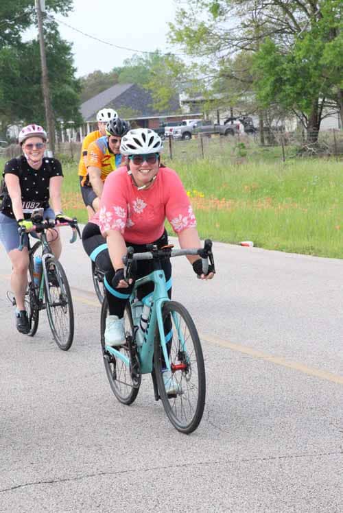 Vibrant group cycling during Bluebonnet Express event on scenic rural road.