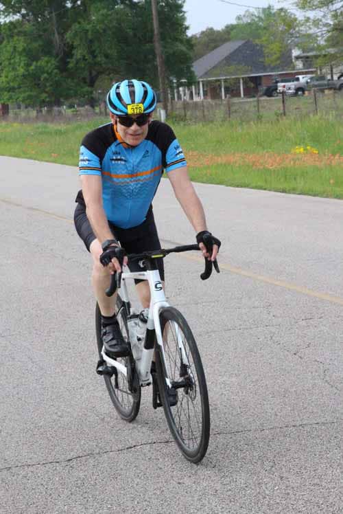 A cyclist riding a road bike on a suburban street during daytime.