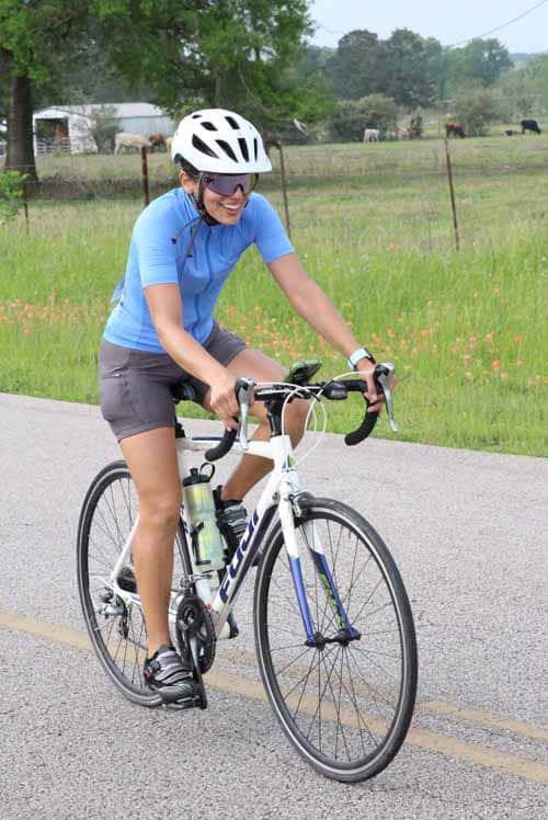 Bright female cyclist enjoying a bike ride on a scenic rural road during daytime.