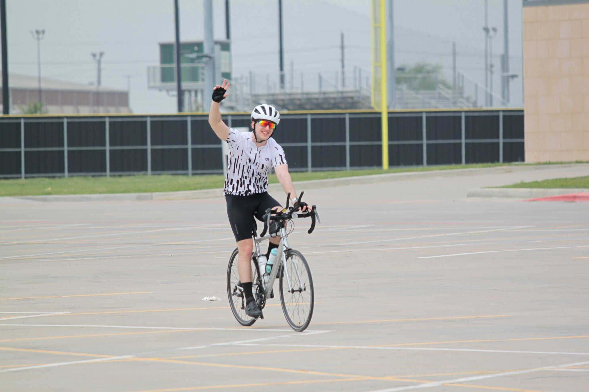 Bright female cyclist celebrating victory, waving after ride on a city street.