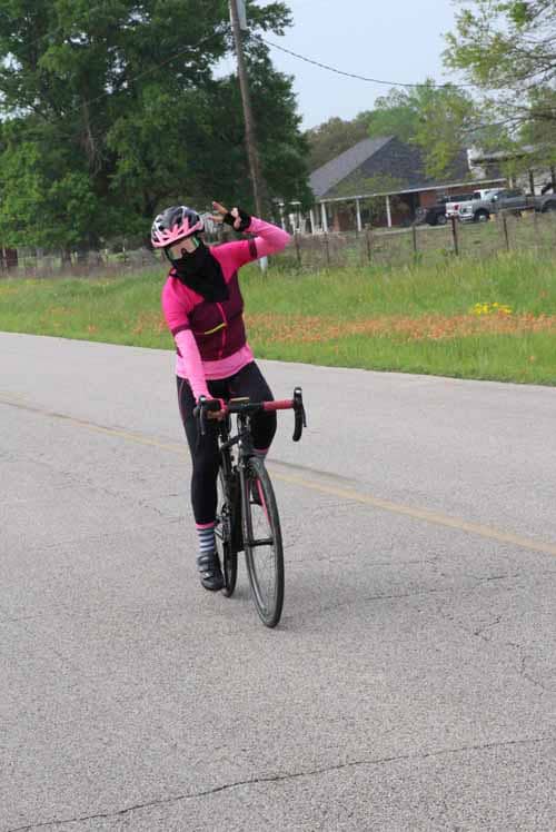 Bright pink cycling outfit with helmet and mask on a road, promoting safe biking.