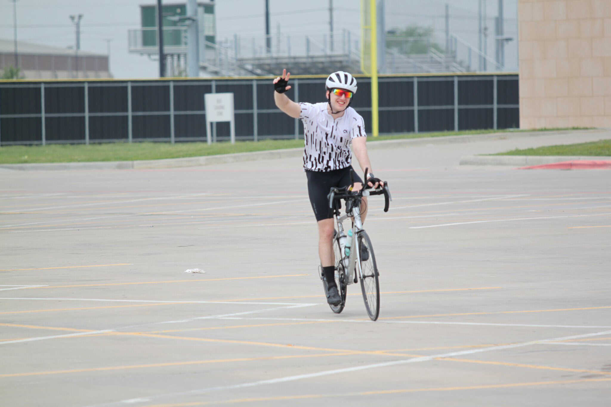 Bike rider waving, riding an electric bicycle on a city parking lot, promoting Bluebonnet Express.