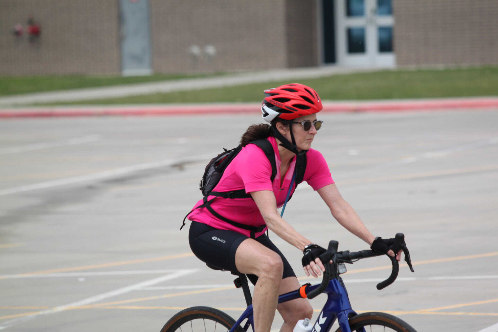 Cyclist in pink riding a bike on a city street during daytime.