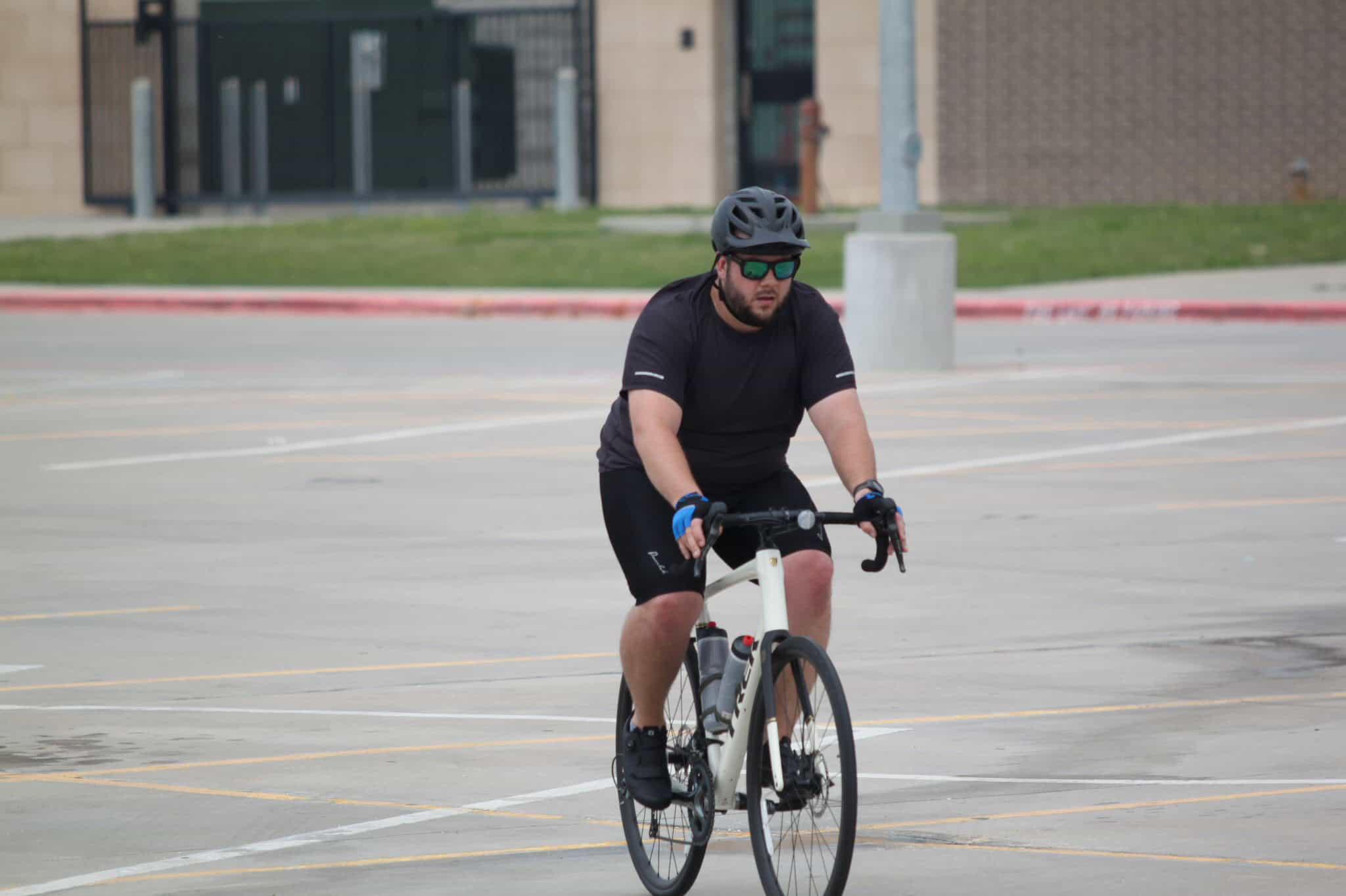 Comfortable man riding a bicycle in an empty parking lot for Bluebonnet Express bike service.