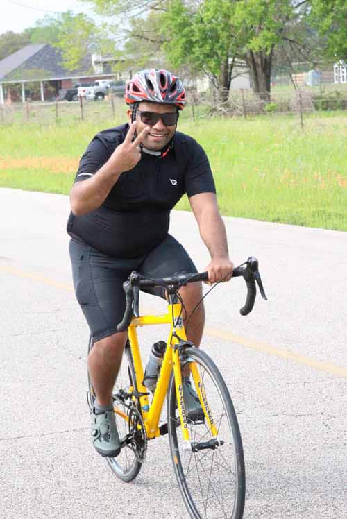 Bright smiling cyclist wearing helmet and sunglasses on yellow bike enjoying outdoor riding.