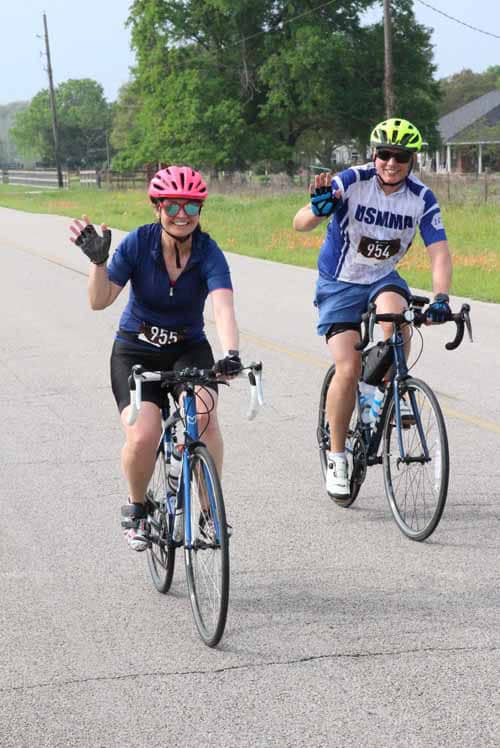 Pink and yellow helmets, smiling cyclists, participating in Bluebonnet Express bike ride, enjoying outdoor endurance event.