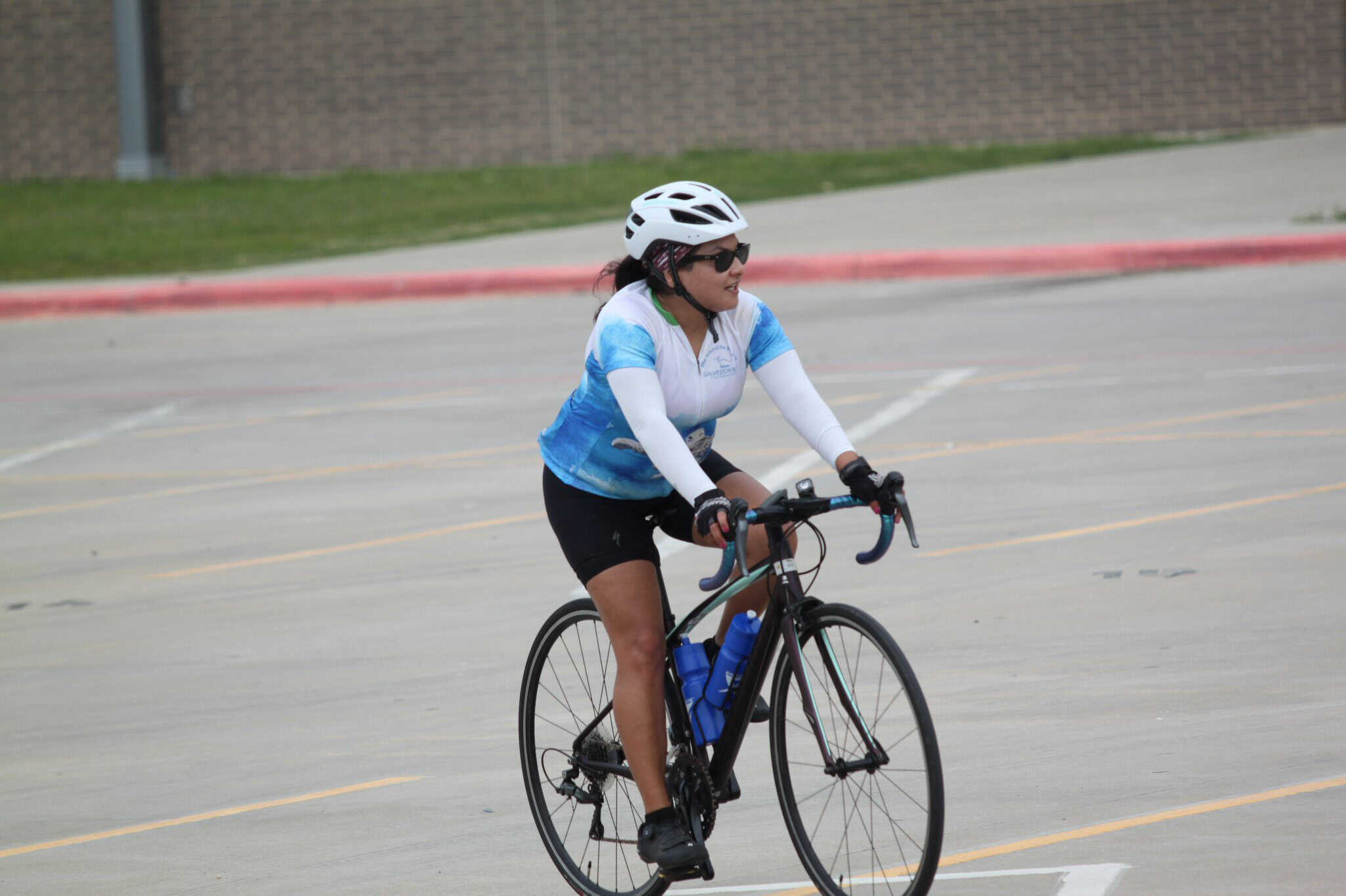 Vegan cyclist riding a bike in a parking lot with a bluebonnet express jersey.
