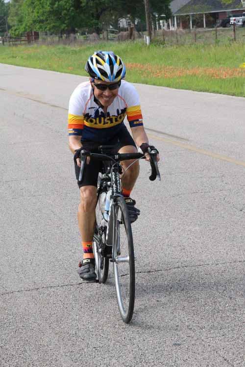 Vibrant cyclist riding on road in bluebonnet express cycling jersey, enjoying smooth ride outdoors.