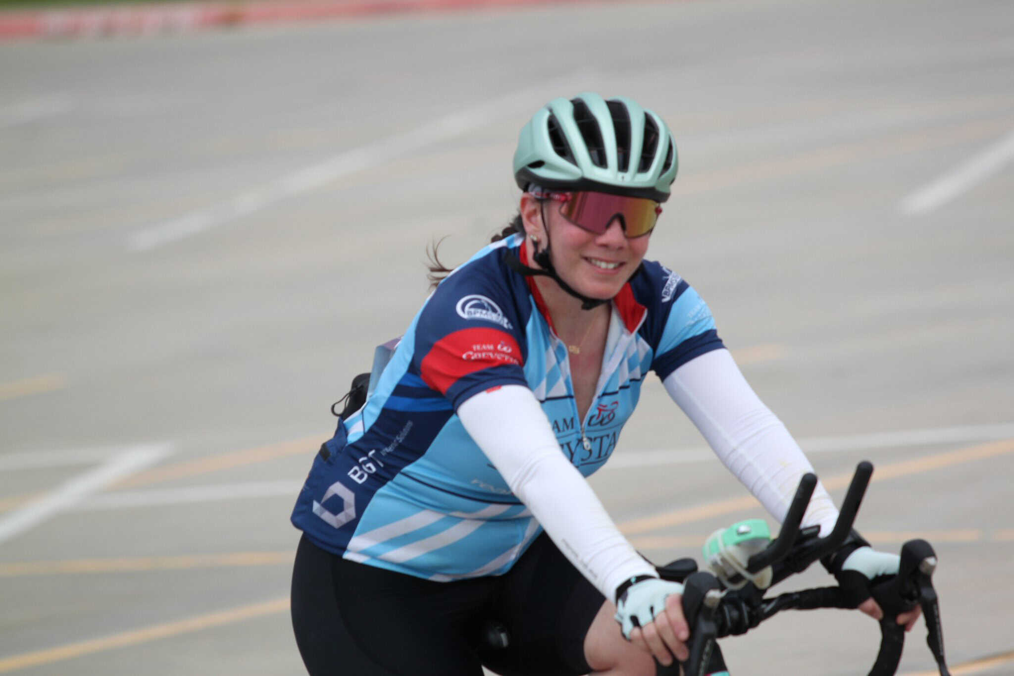 Bright female cyclist smiling, wearing helmet and sunglasses on Bluebonnet Express route, showcasing outdoor biking adventure.