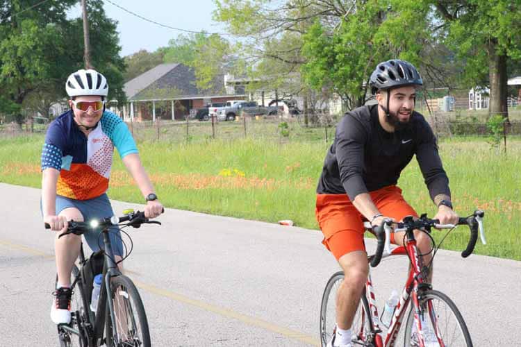 Brightly dressed cyclists enjoying a ride on a scenic bike path with lush greenery.