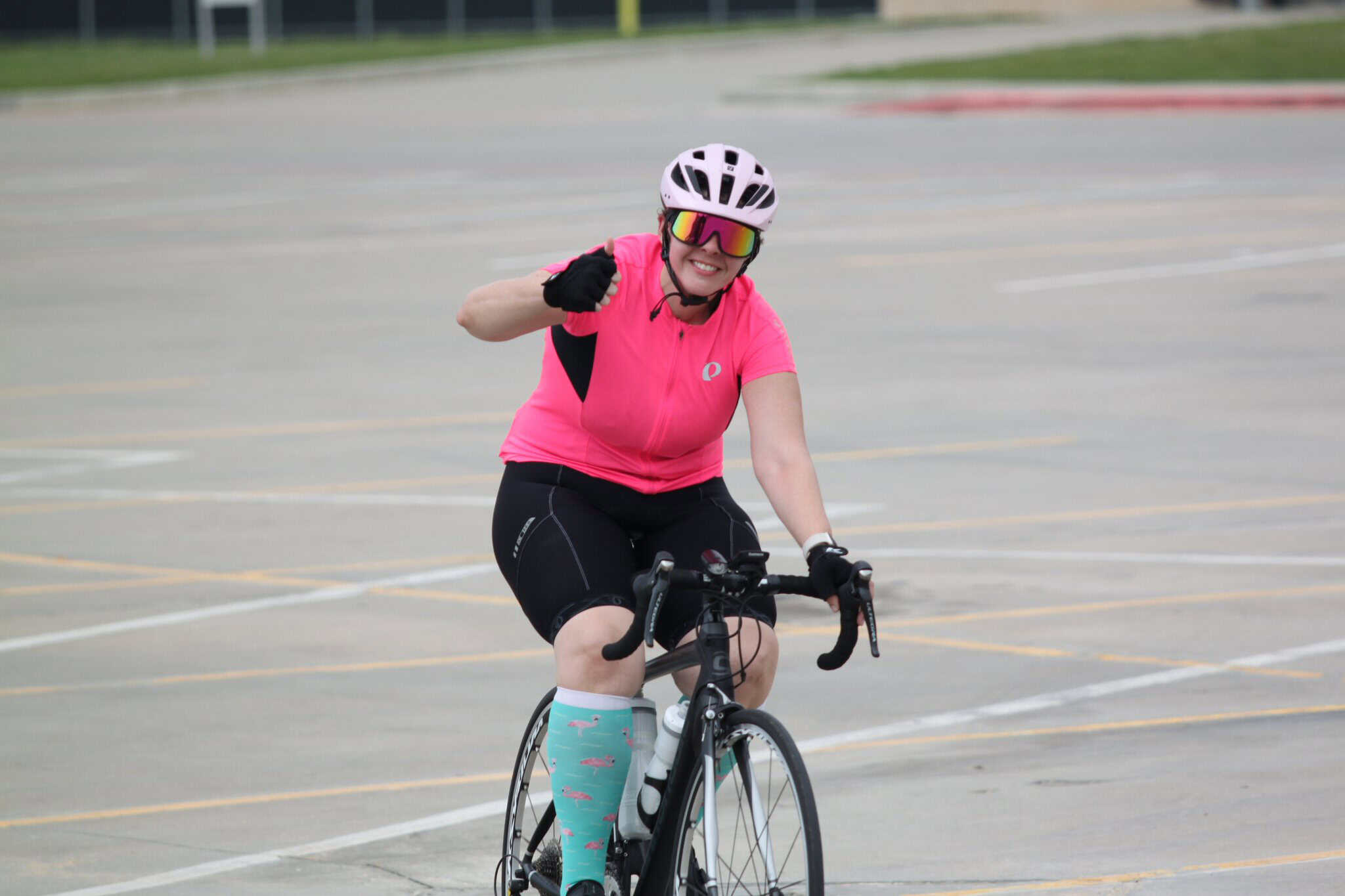 Vibrant woman cycling outdoors, wearing pink sportswear and helmet, enjoying urban bike ride.