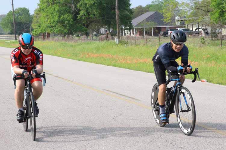 Brightly dressed cyclists enjoying a ride on a sunny rural road for Bluebonnet Express event.