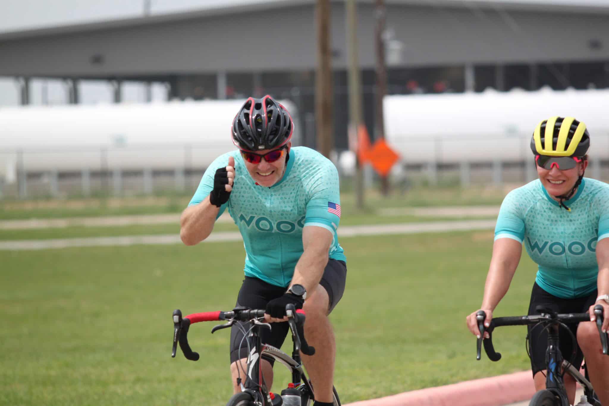High-performance cyclists riding on the road, wearing colorful jerseys and helmets for Bluebonnet Express event.