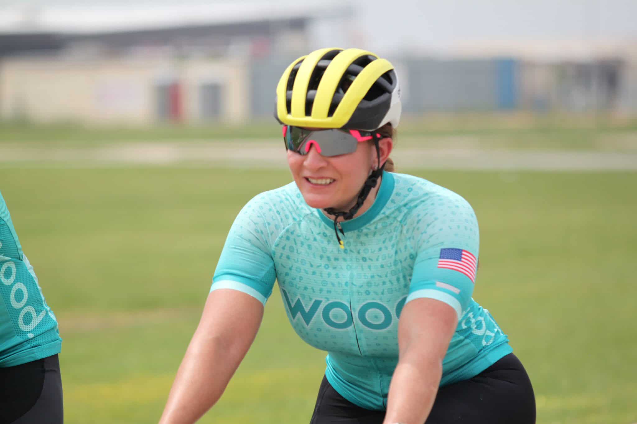 Bright female cyclist wearing Bluebonnet Express team jersey and safety gear during outdoor bike race.