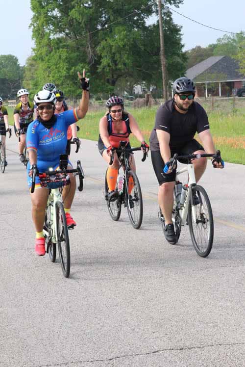 Group of cyclists enjoying Bluebonnet Express bike ride on scenic rural road, promoting outdoor activity and community health.