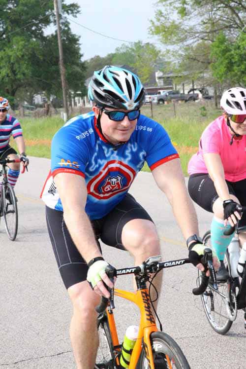 Bright blue cyclist jersey with Louisiana state emblem and blue helmet at Bluebonnet Express bike ride event.