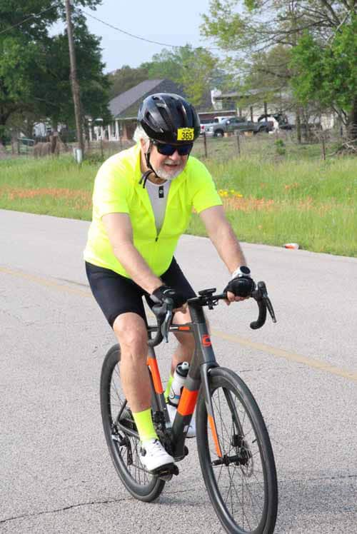 Bright yellow cyclist jersey and helmet riding a road bike on a suburban street.
