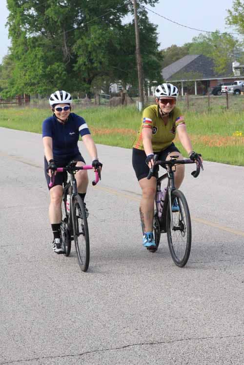 Brightly dressed cyclists enjoying a ride during daytime in a rural setting with greenery.