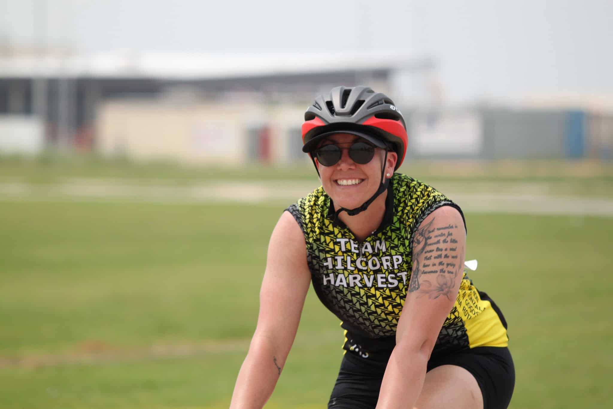 Bright smiling female cyclist wearing helmet and sunglasses at Bluebonnet Express event.