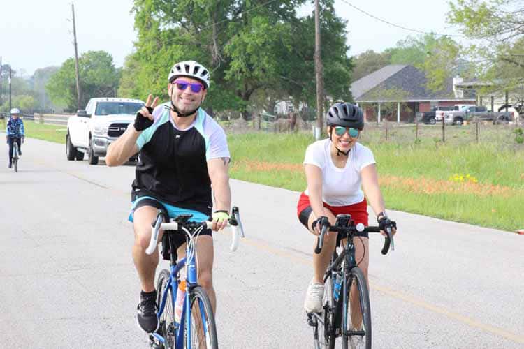 Vibrant cyclists enjoying Bluebonnet Express bike ride on scenic rural road.