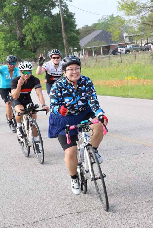 Cheerful cyclists riding on a scenic road during Bluebonnet Express event in Texas.