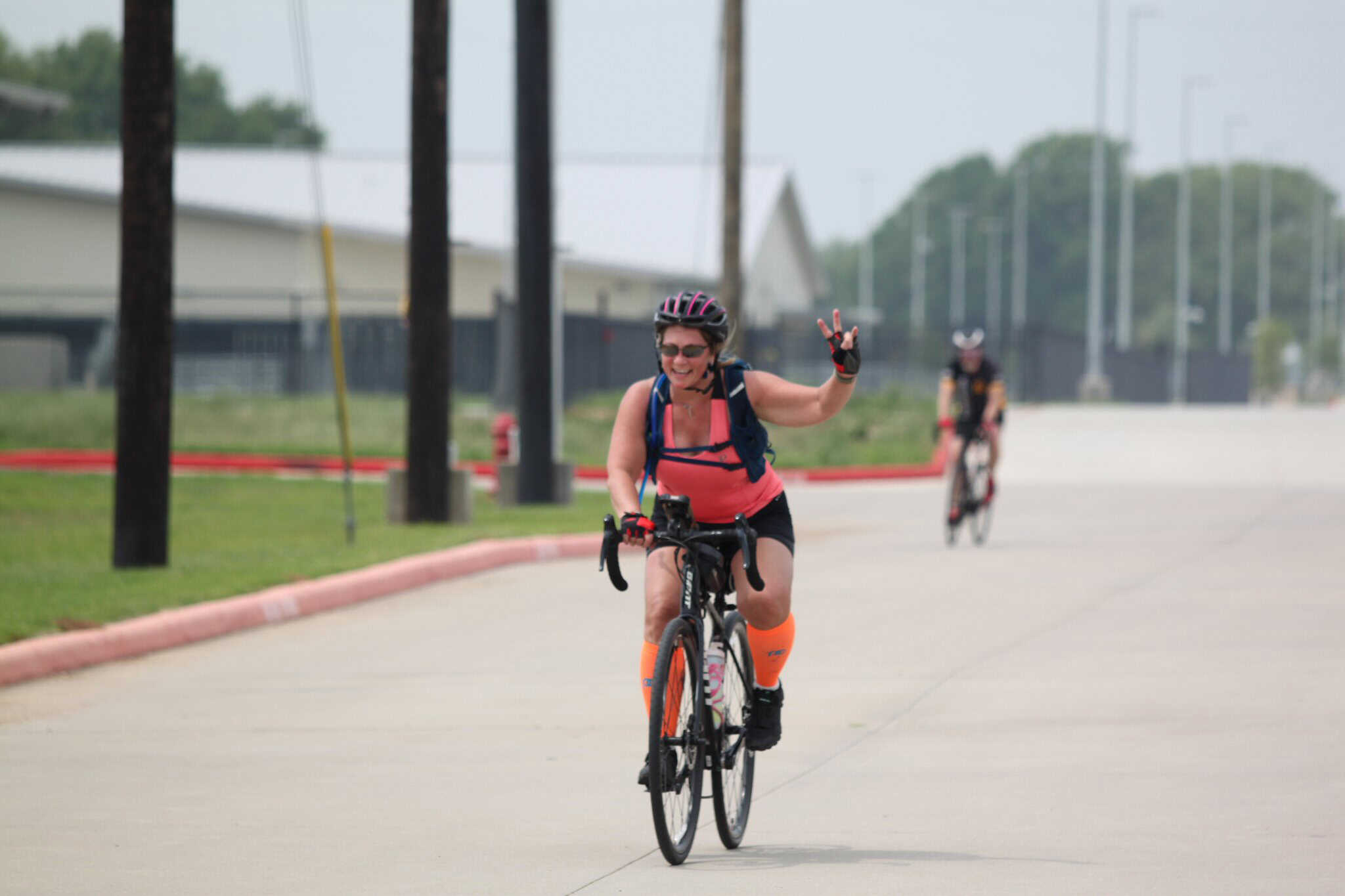 Bright woman riding a bicycle with a peace sign at Bluebonnet Express bike event.