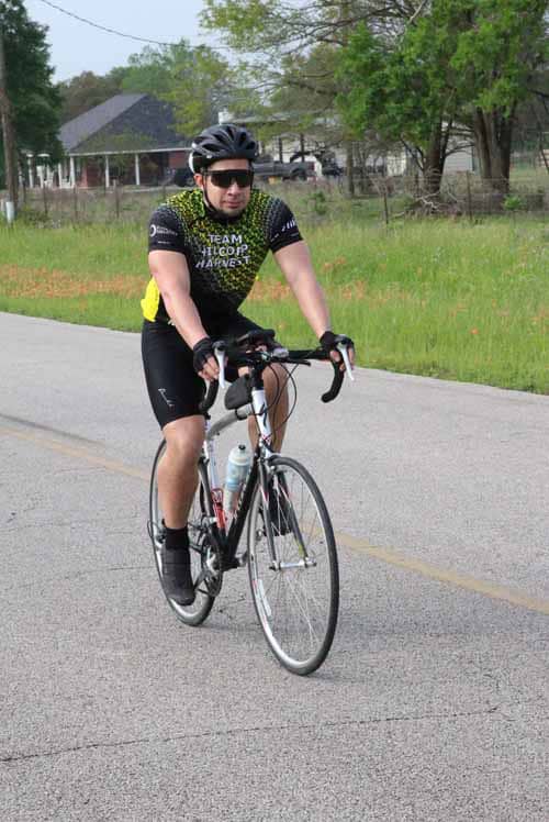 Bright male cyclist riding bikes during daytime in rural area for Bluebonnet Express event.