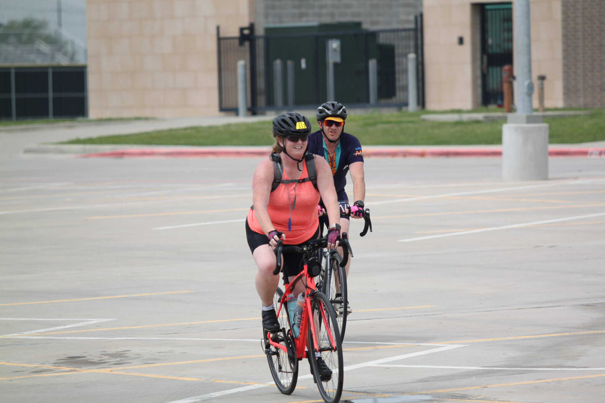 Women cycling at Bluebonnet Express event in a parking lot, promoting health and outdoor activity.