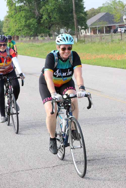 Bright female cyclist smiling during Bluebonnet Express bike ride in Texas, wearing colorful cycling gear.