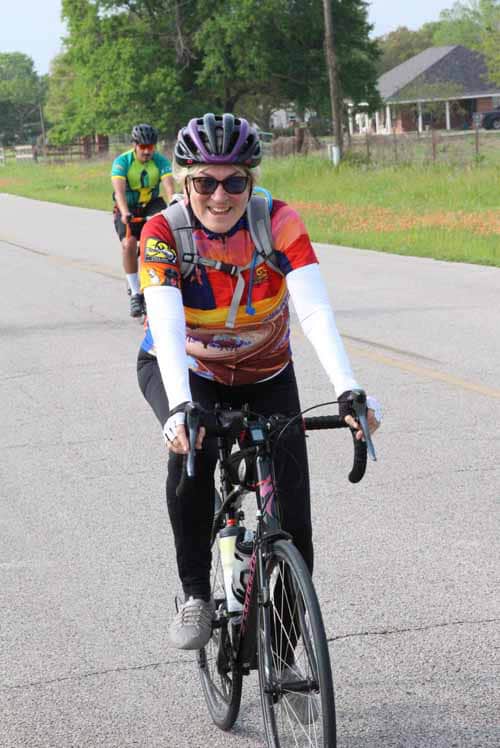 Bright cyclist smiling on road during Bluebonnet Express event, enjoying a scenic bike ride.