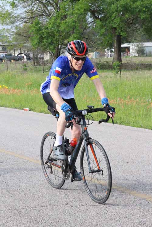 1. Man riding a bicycle wearing a blue cycling jersey and helmet outdoors.