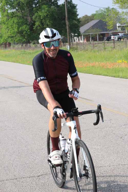 Vibrant cyclist riding on a suburban road during daytime, showcasing Bluebonnet Express bike service.