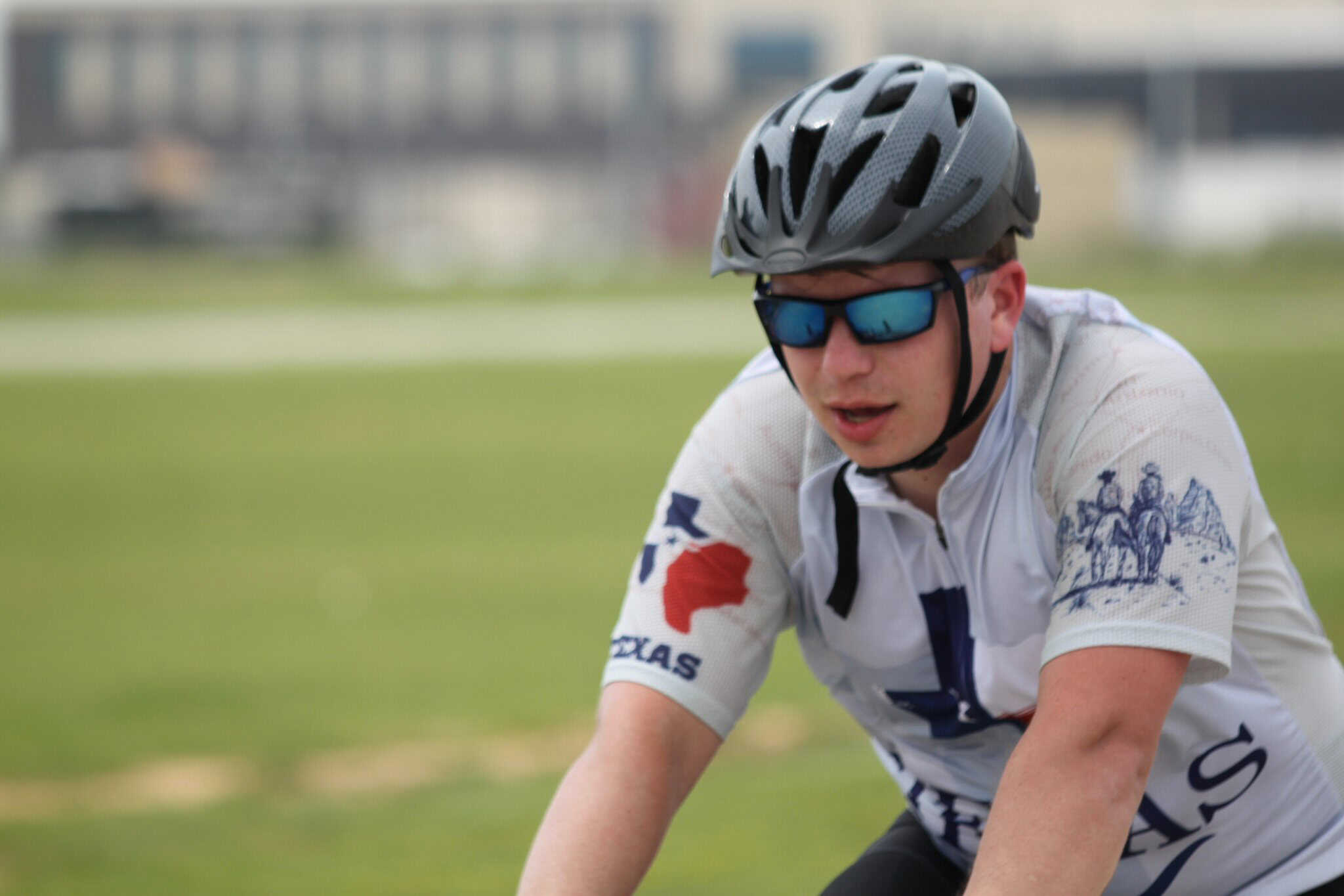 Rider on a bicycle wearing helmet and sunglasses during Bluebonnet Express biking event.